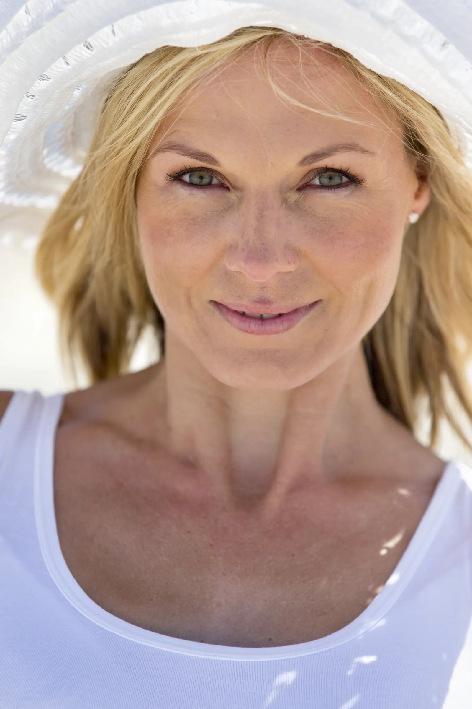 Blonde woman wearing a white hat smiling