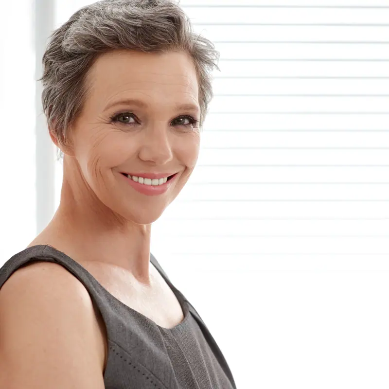 Elegant woman smiling with short grey hair indoors
