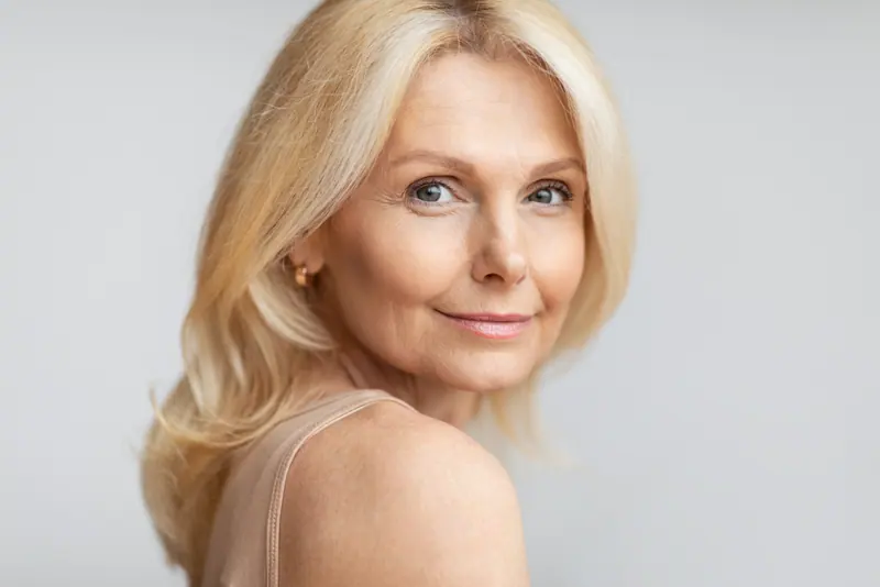 Elegant woman with wavy blonde hair posing indoors