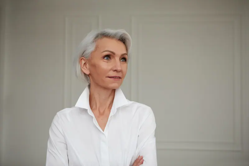 Mature woman poses in white shirt indoors