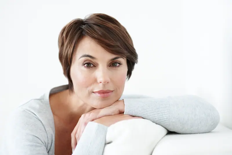 Mature woman with short brown hair posing indoors