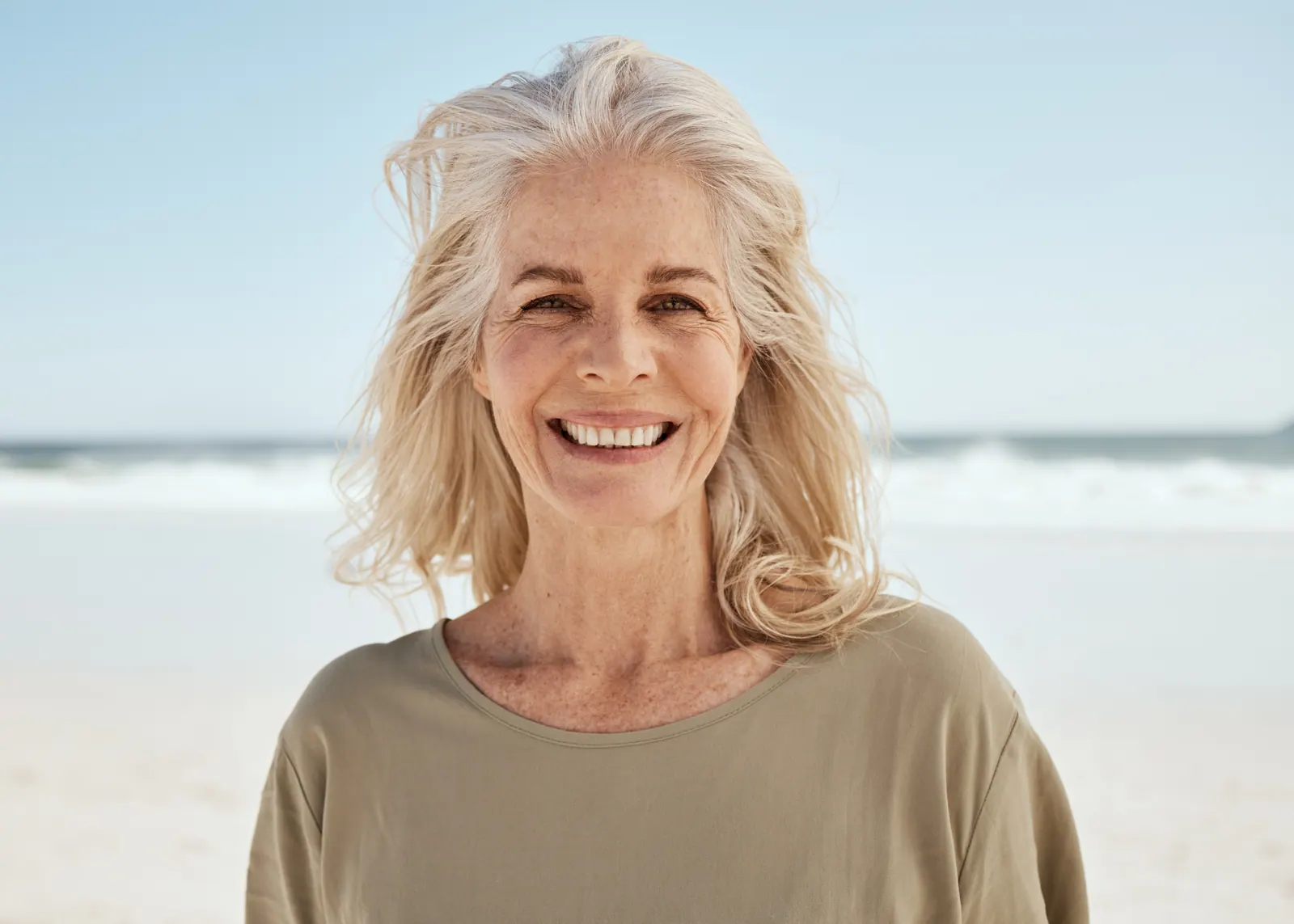 Senior woman smiling on a bright beach day