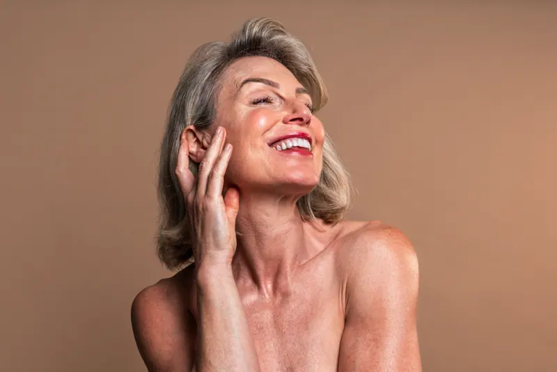 Smiling mature woman posing with hand on face