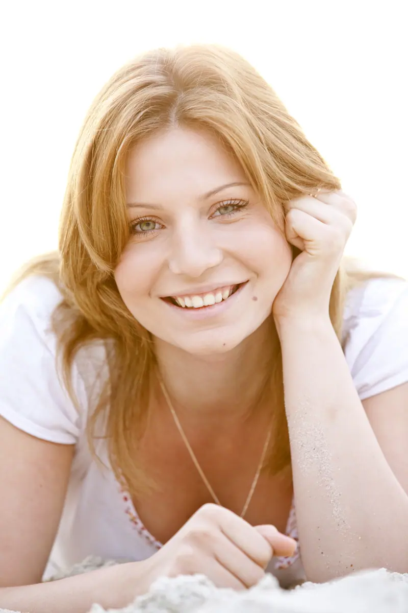 Smiling woman with blonde hair posing on sand