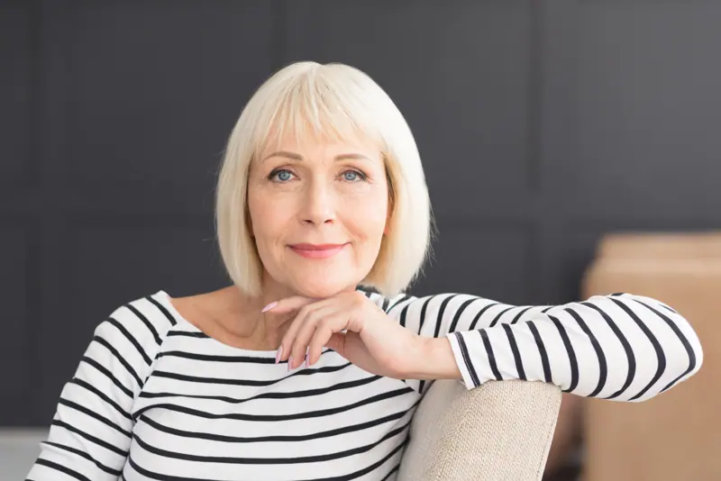 Smiling woman with blonde hair sitting indoors