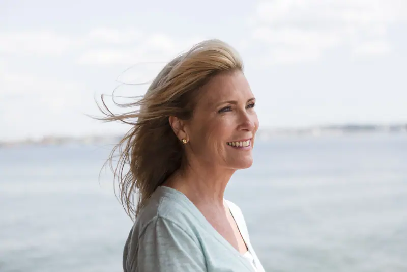 Smiling woman with windblown hair near the water
