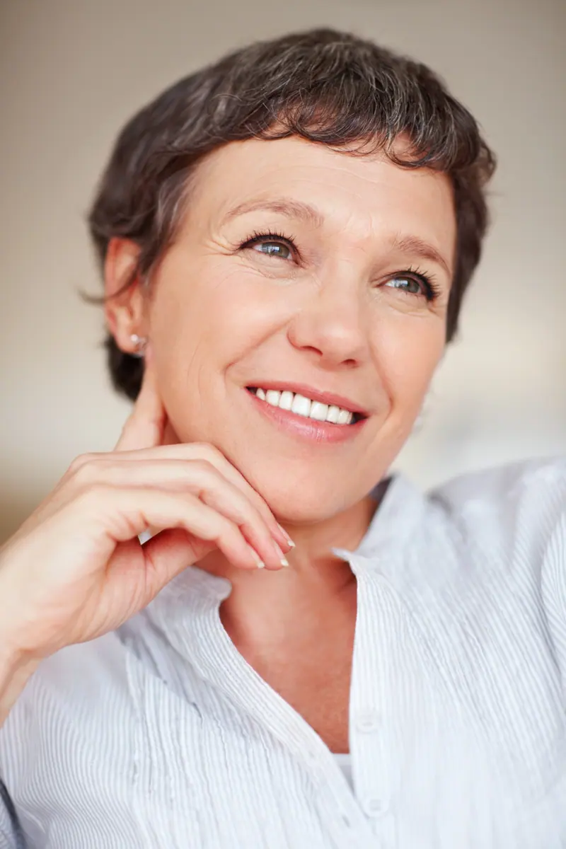 Thoughtful woman with gray hair smiling indoors