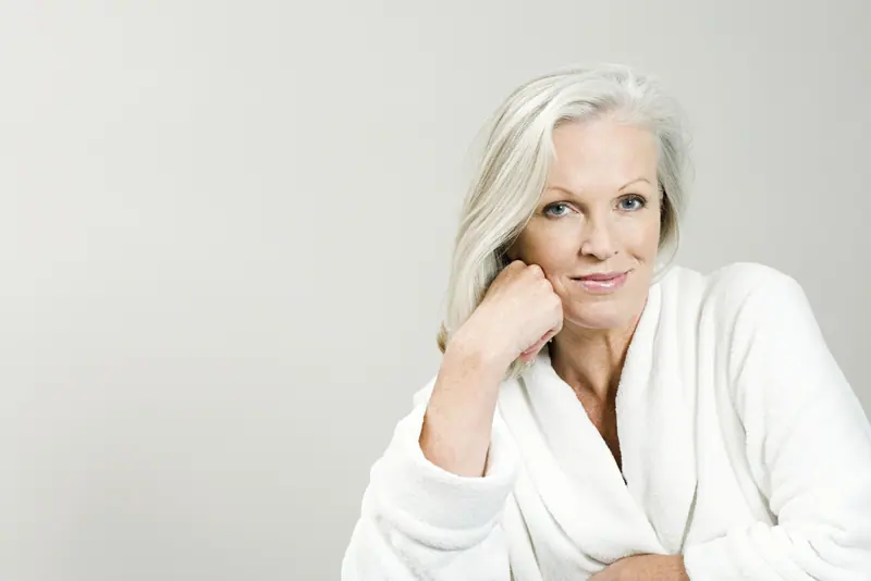 Woman in white robe posing serenely indoors