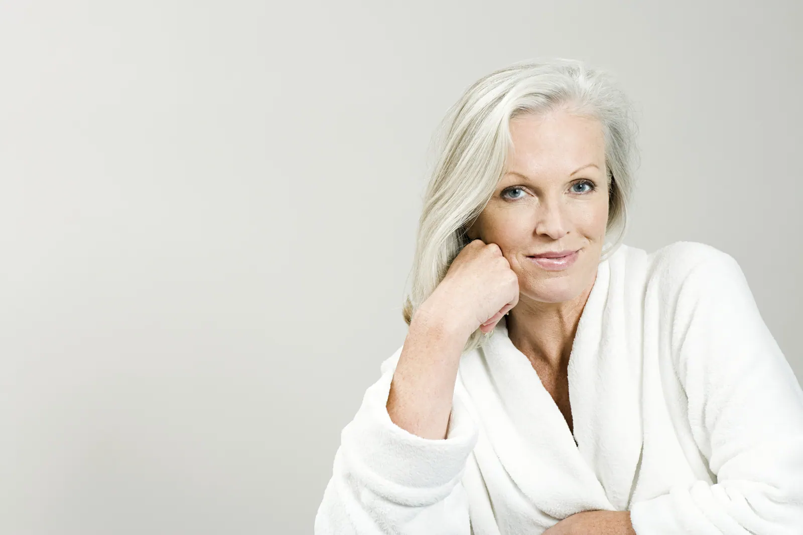 Woman in white robe posing serenely indoors