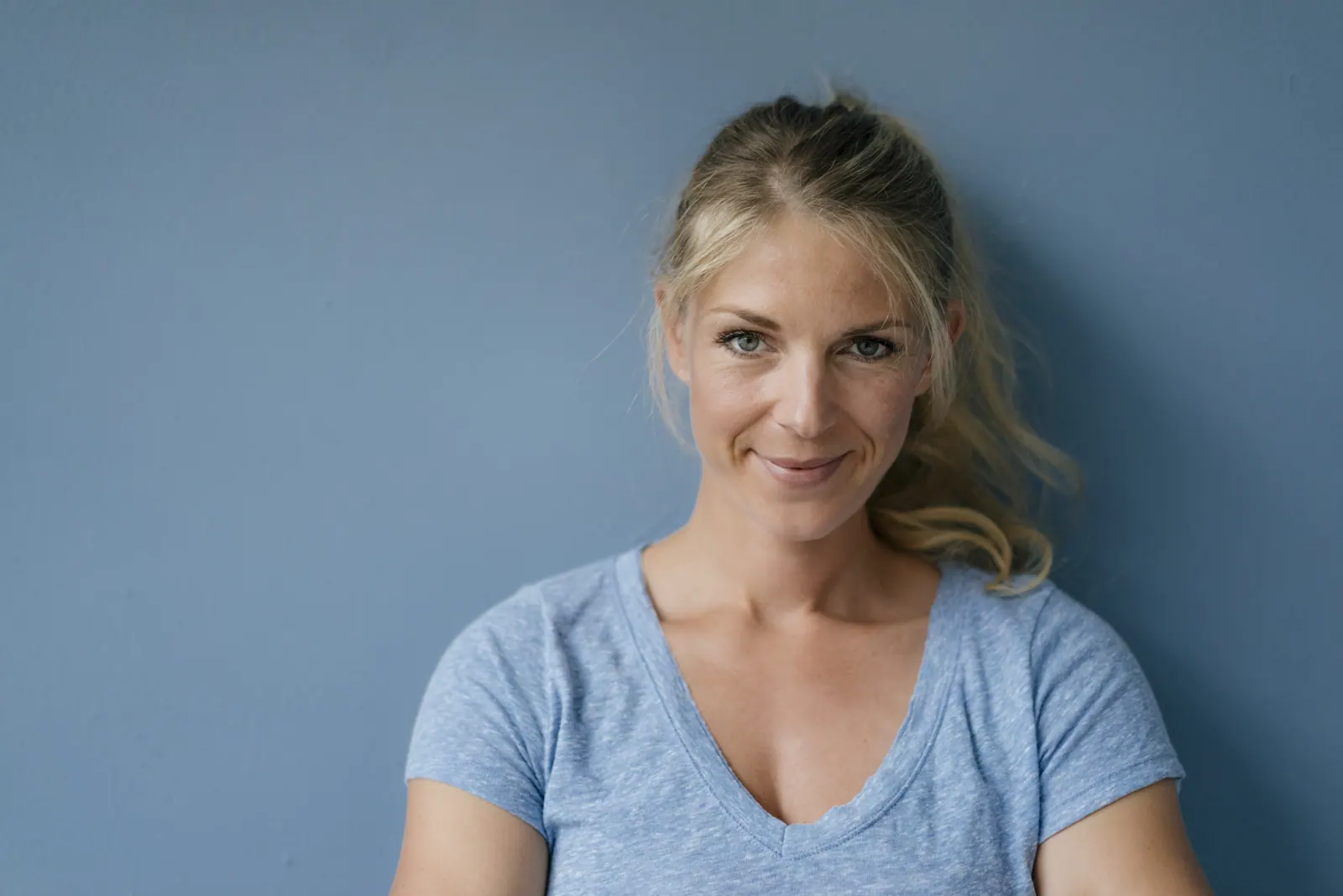 Woman smiling against a blue wall in studio