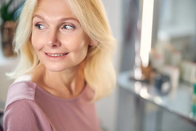 Woman with blond hair smiling in room